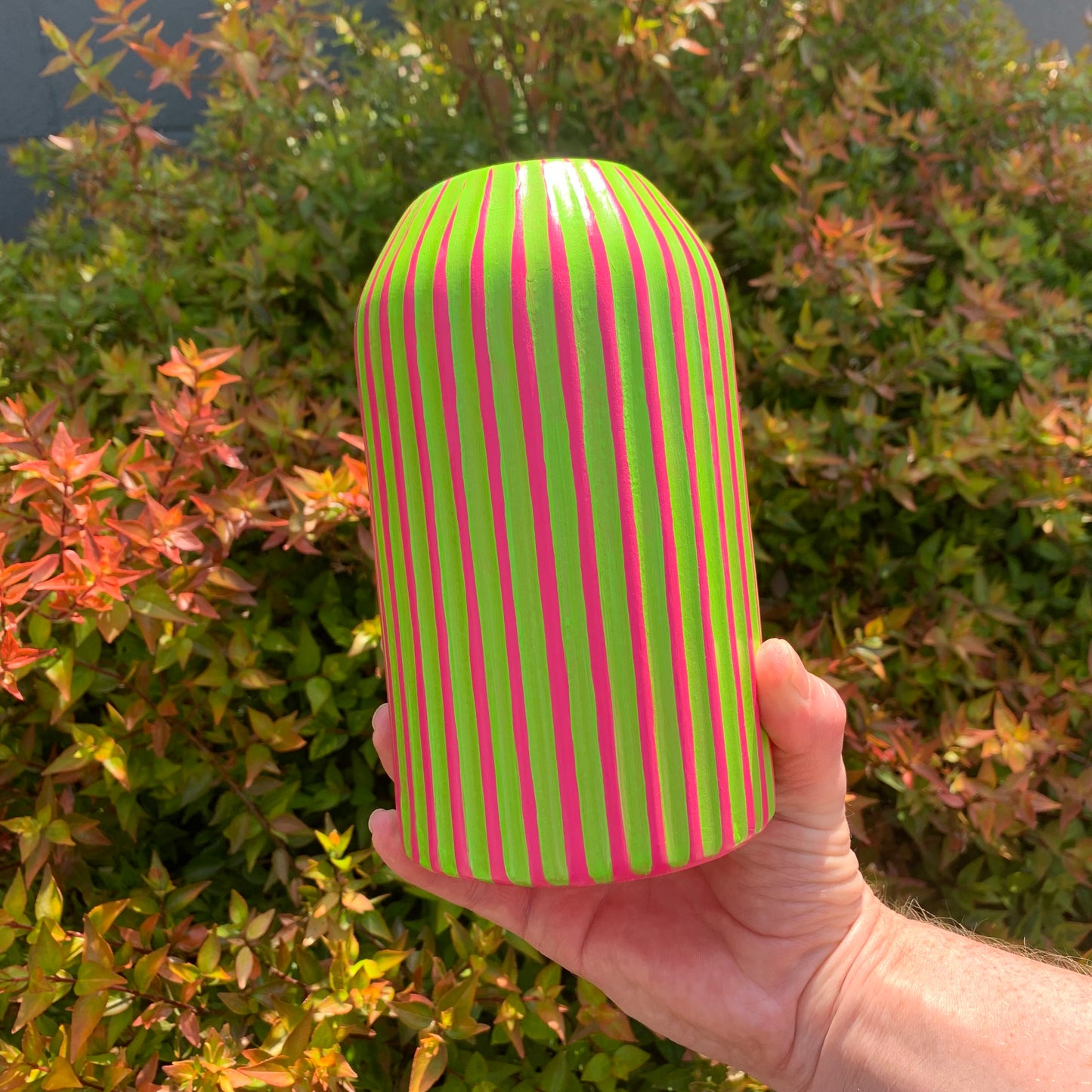 A hand painted fuchsia based vase with green stripes