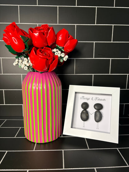A hand painted green based vase with fuchsia stripes, accompanied by a small pebble art frame containing the phrase 'Always & Forever'