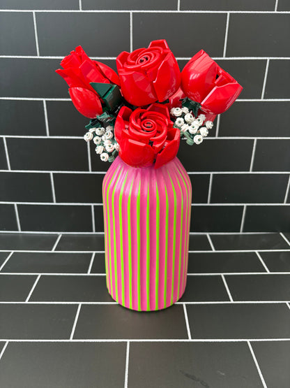 A hand painted green based vase with fuchsia stripes