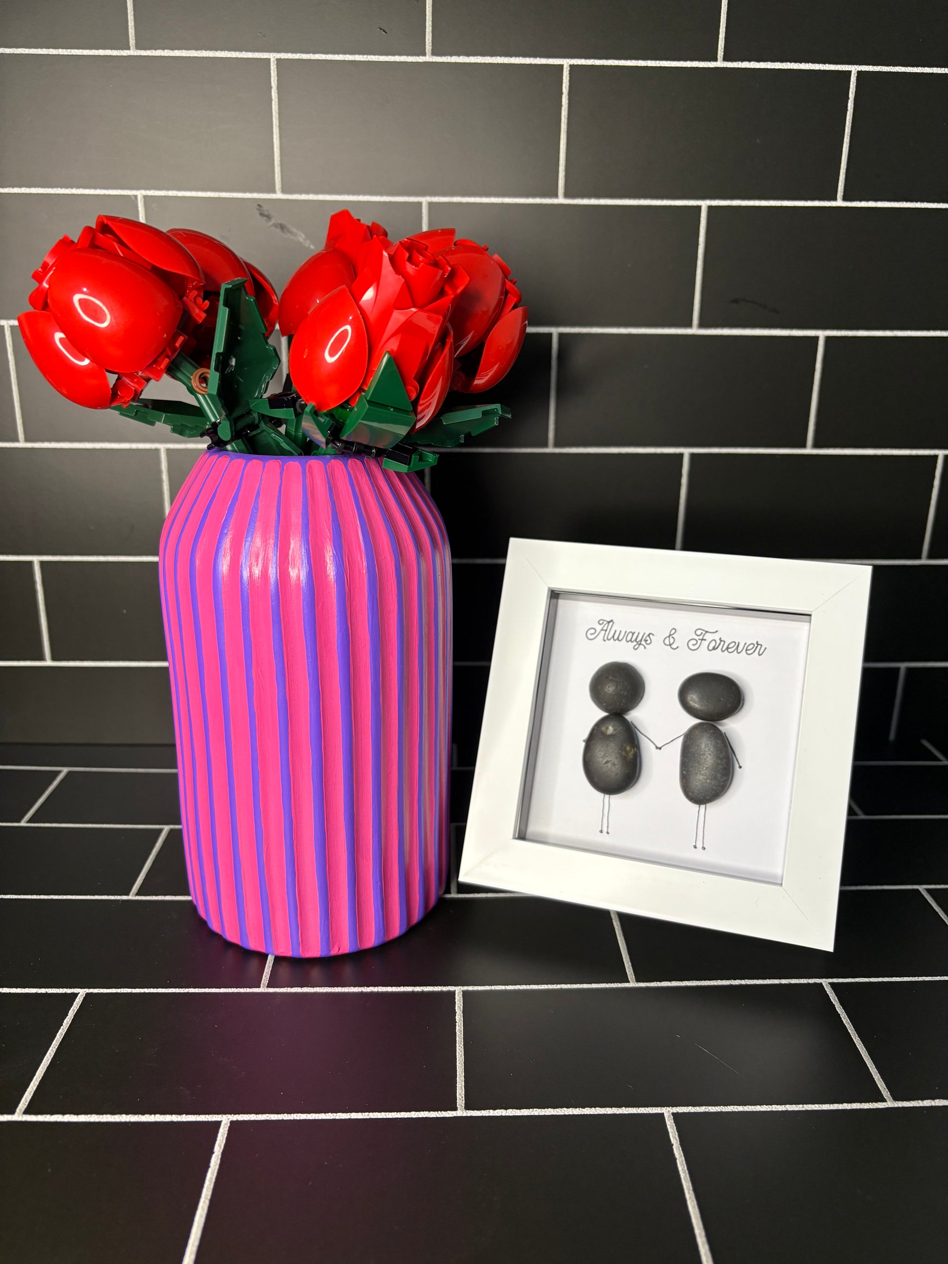 A hand painted purple based vase with fuchsia stripes, accompanied by a small pebble art frame containing the phrase 'Always & Forever'