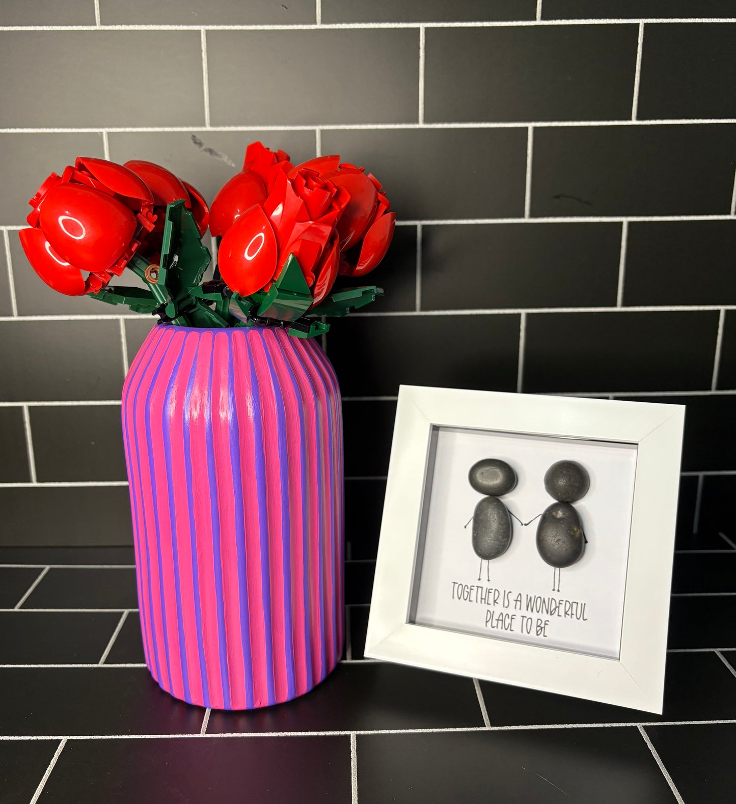 A hand painted purple based vase with fuchsia stripes, accompanied by a small pebble art frame containing the phrase 'Together Is A Wonderful Place To Be'