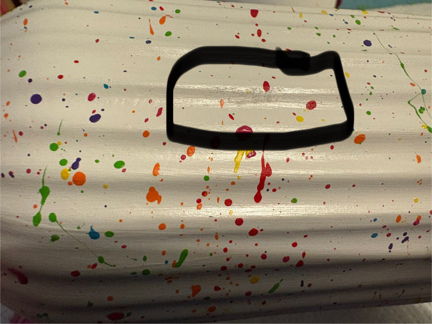 A ceramic rainbow splatter vase with a slight blemish where the primer hasn't covered well. This area is circled with a black marker.